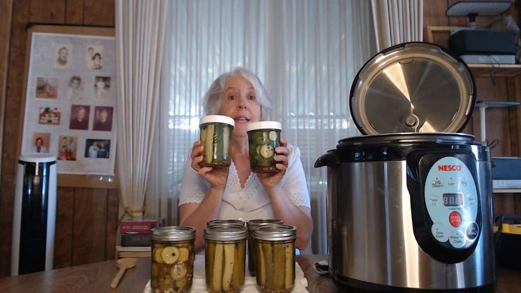 Holding up some jars of home canned dill pickles
