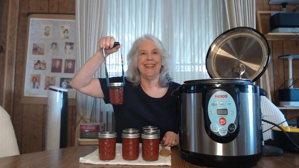 Holding up a jar of home-canned taco sauce