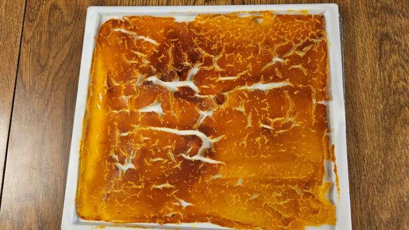 A dehydrator tray filled with fully dehydrated pumpkin puree.