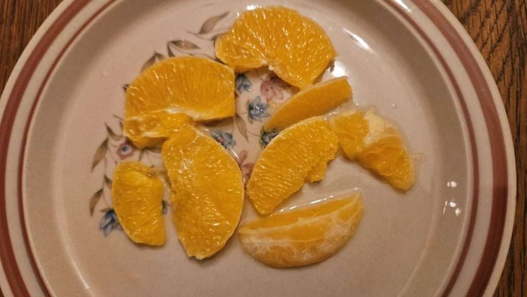 Thawed orange pieces on a plate showing juice released during thawing