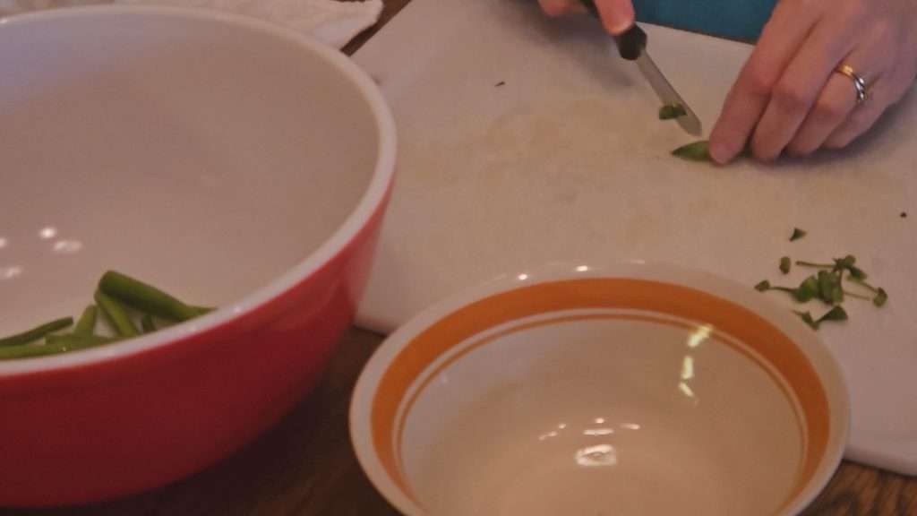 cutting off the ends of green beans and cutting them into 2" pieces.