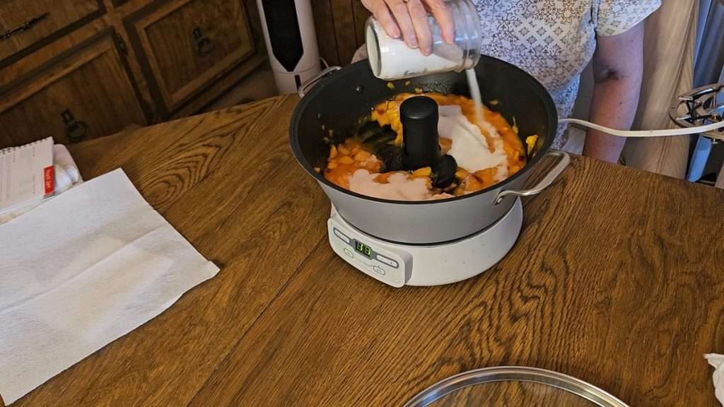 Pouring sugar on top of the nectarines in the Ball Jam and Jelly maker.