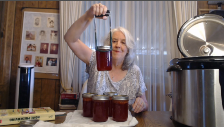 Holding up strawberry lemonade concentrate in a mason jar