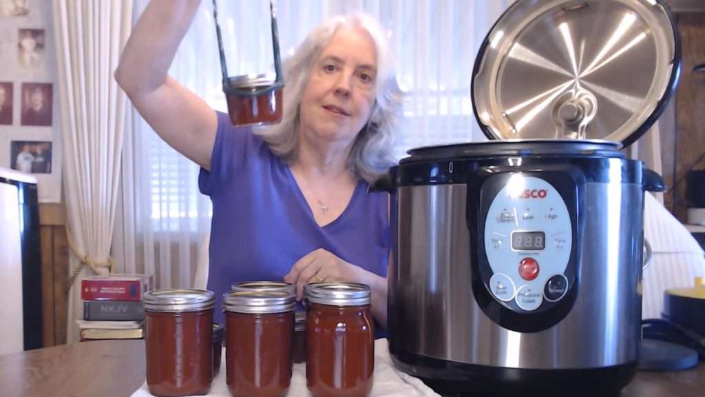 Holding up a jar of sweet and spicy bbq sauce, after processing.