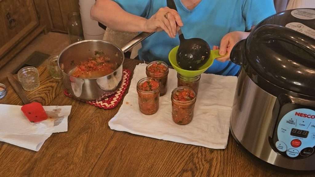 Filling half-pint canning jars with salsa ranchera