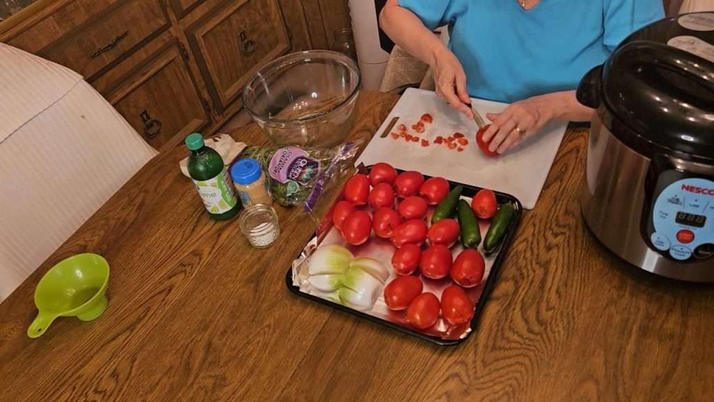 Raw tomatoes, jalapenos, and onions on a baking sheet to be roasted for salsa ranchera.