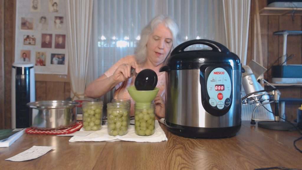 Adding syrup to grapes in canning jars