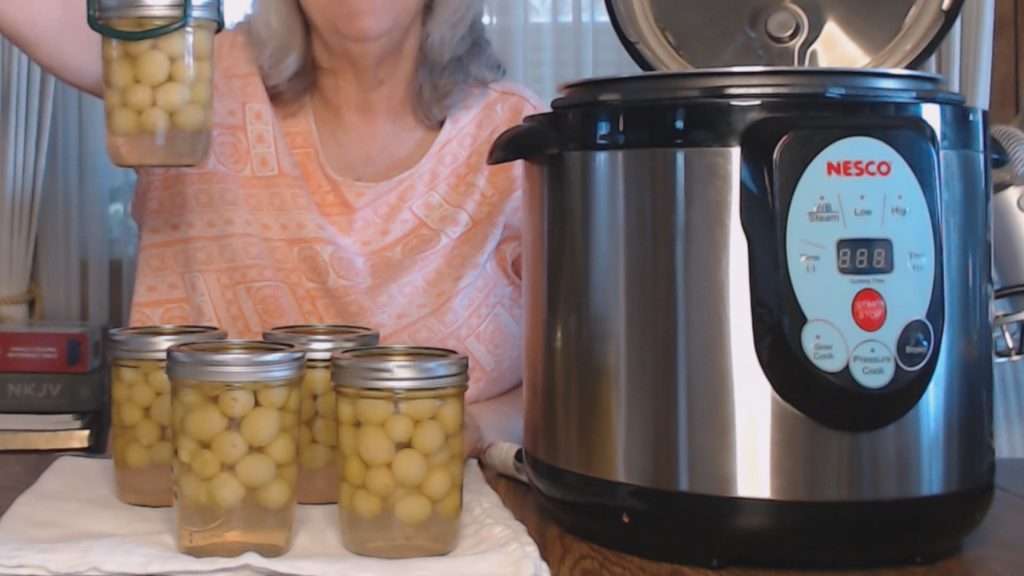 Holding up a jar of home canned grapes.