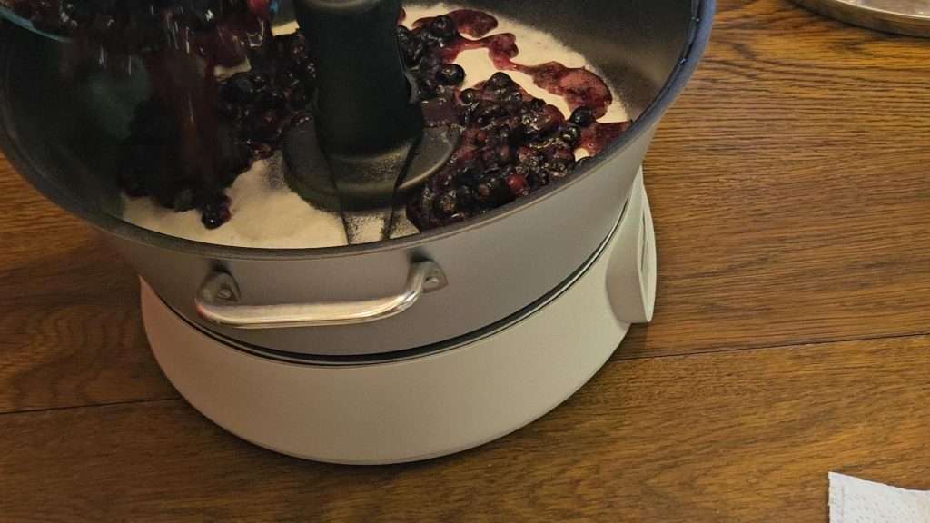 Pouring crushed blueberries into the ball jam and jelly maker.