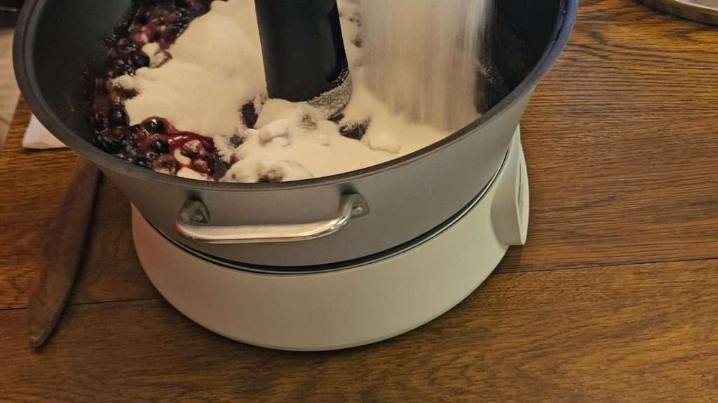 Pouring the sugar into the berries and pectin in the ball jam and jelly maker.