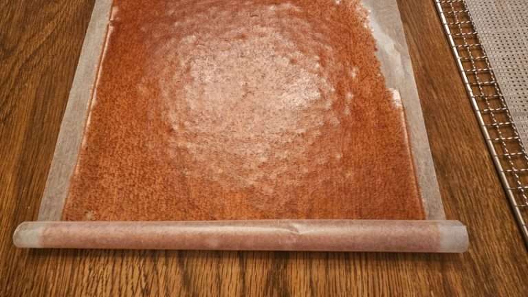 Grape fruit leather that is just starting to be rolled up in wax paper.