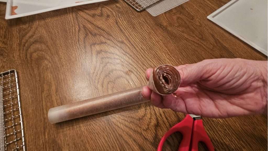 top view of cut grape fruit leather that is rolled up in wax paper.