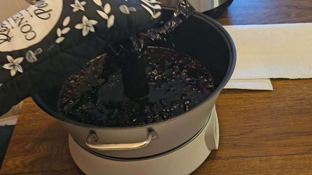 Using a pot holder to remove the stirrer. when canning blueberry jam, the jam gets very hot, so use care when removing the stirrer.