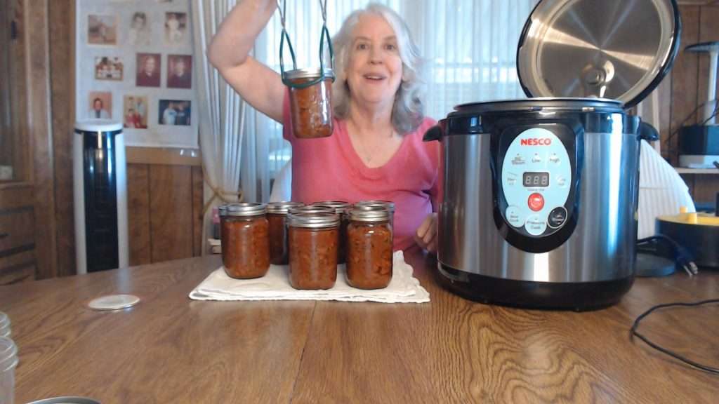 holding up a jar of home-canned chili con carne.