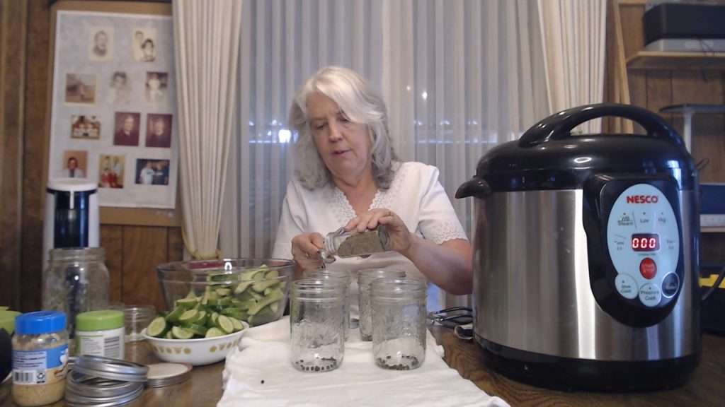 Measuring out dill seed into canning jars.