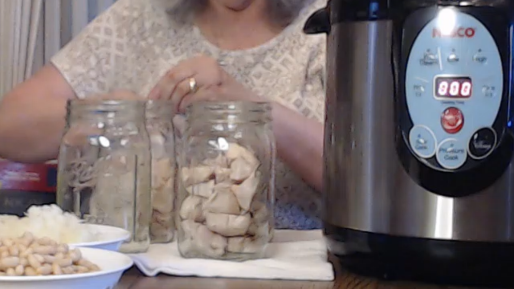 Adding partially cooked chicken into canning jars.