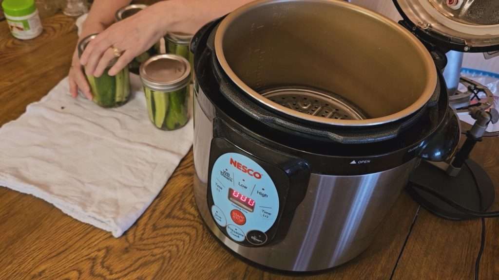 Putting a canning lid on a jar of cucumber spears.
