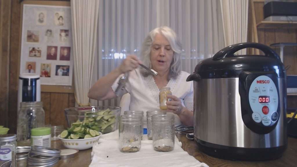Putting jarred minced garlic into canning jar.