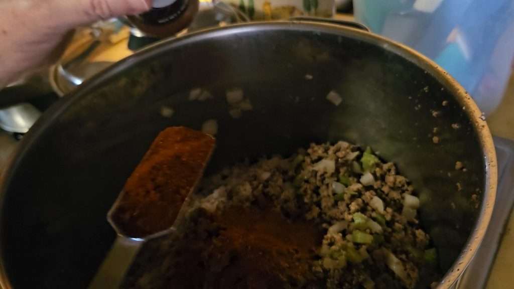 A pot filled with browned ground beef, with onions and bell peppers. 