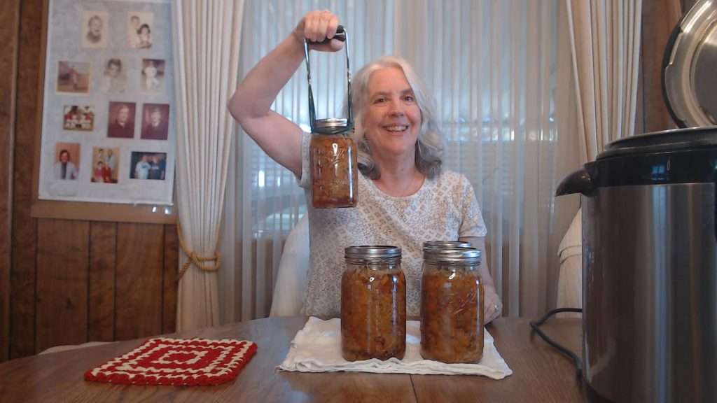 hold up a mason jar with chicken and gravy in a jar