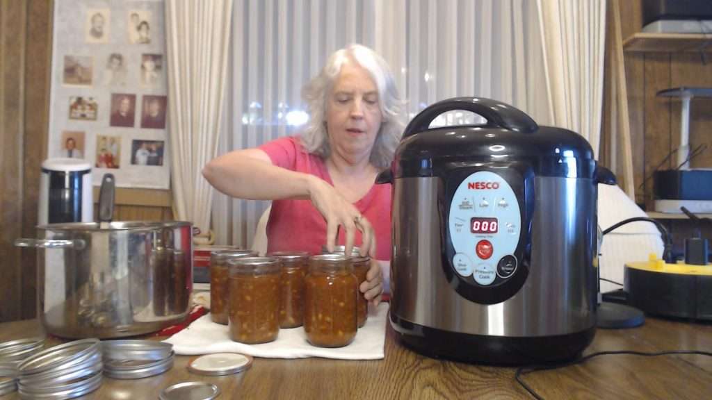 putting the lids on canning jars filled with chili con carne