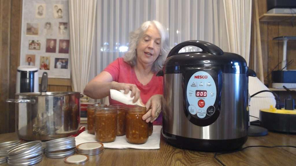 wiping the rims of mason jars filled with chili con carne
