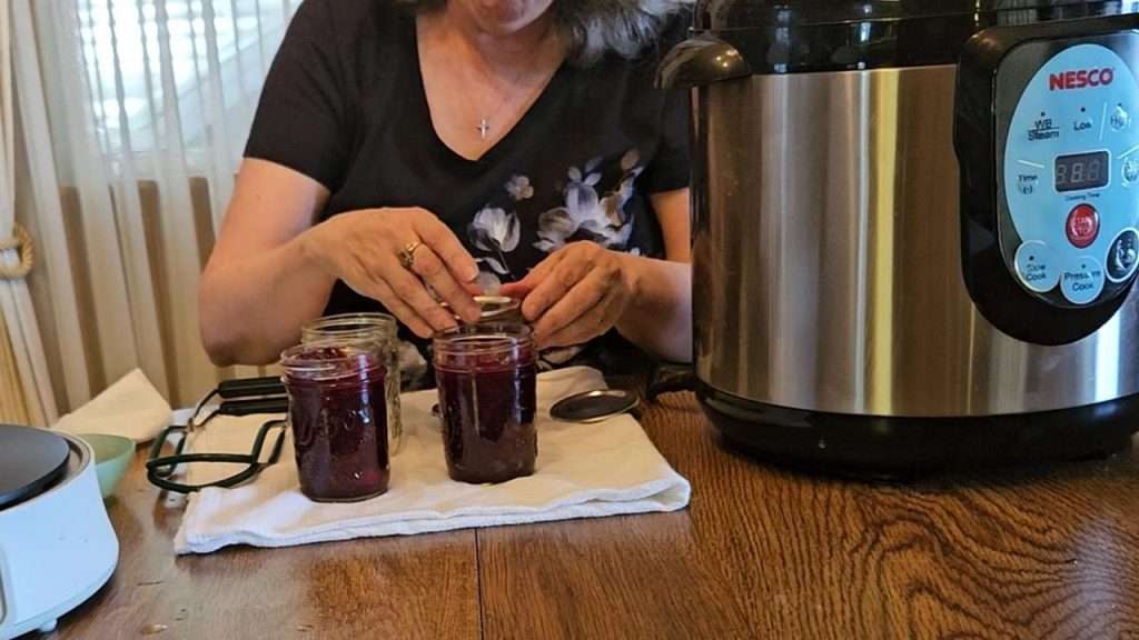 Putting the lids on canning jars filled with cranberry sauce.