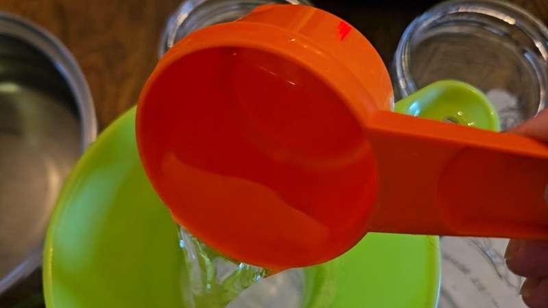 Syrup being poured through a funnel into an empty mason jar