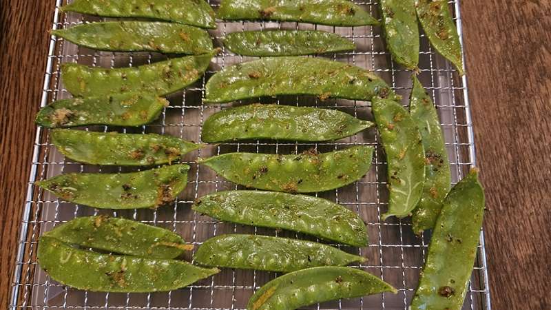 Snow peas laid out on dehydrator trays for drying.