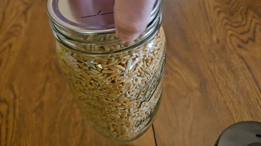 Lifting up a jar of vacuum sealed wheat berries by the lid to show the jar was well sealed. 
