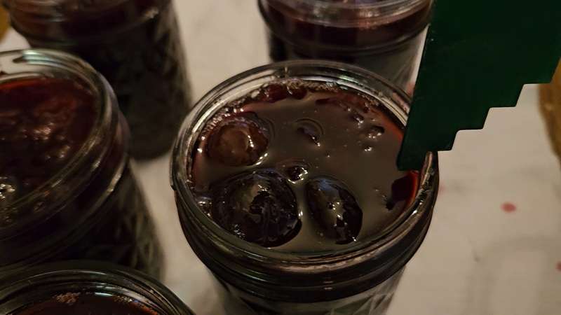 Checking the headspace in a jar of homemade cherry jam.
