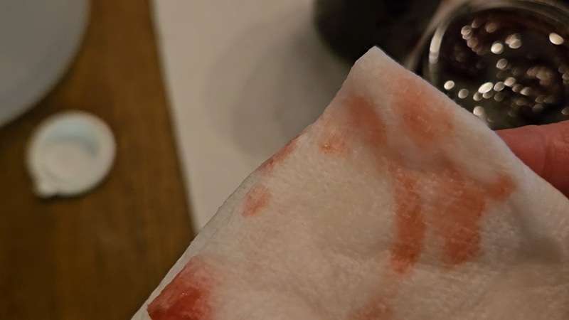A paper towel with cherry jam that was left on the paper towel as a result of wiping the rims.