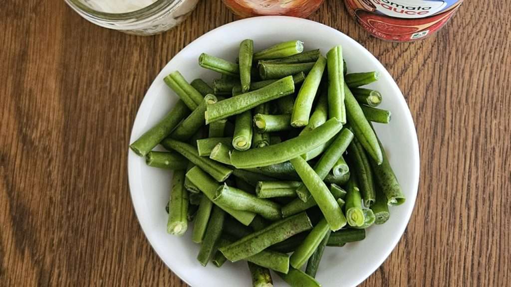 A bowl of green beans that are trimmed, cut into 1 - 2" pieces.