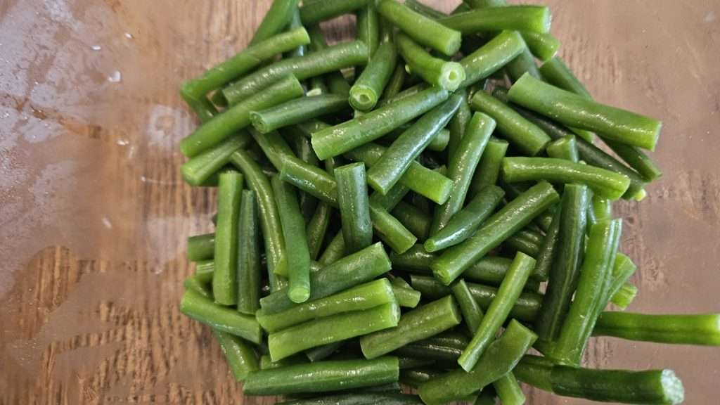 drained green beans in a clear glass bowl.