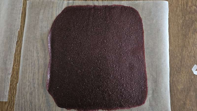 A sheet of cherry fruit leather placed on a large piece of wax paper.