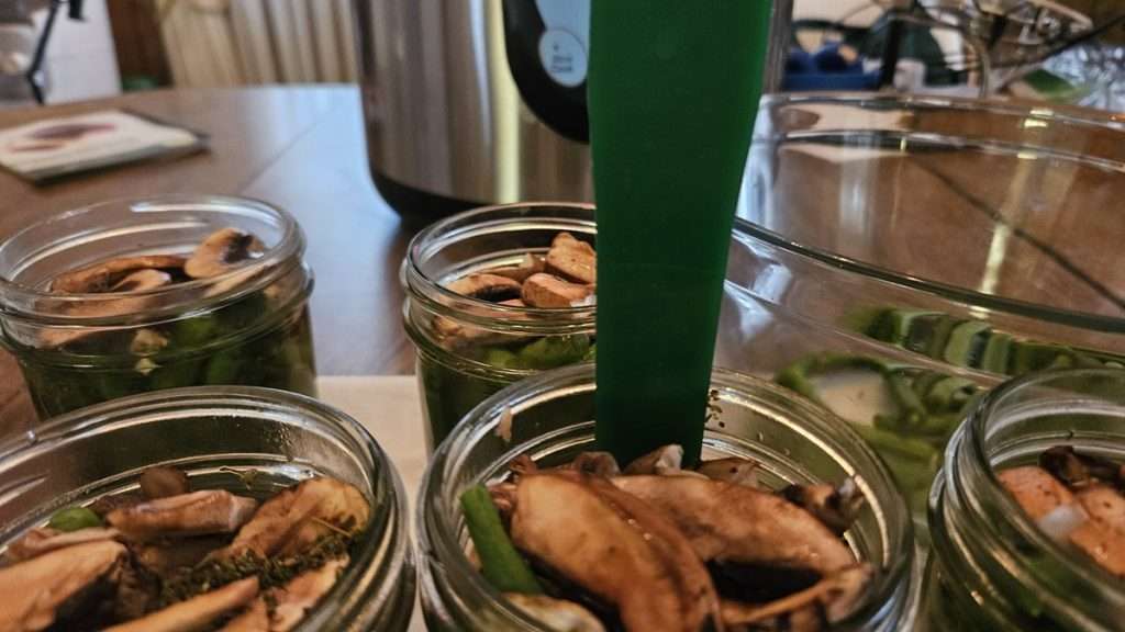 Using a debubbler tool to debubble a canning jar with green beans and mushrooms