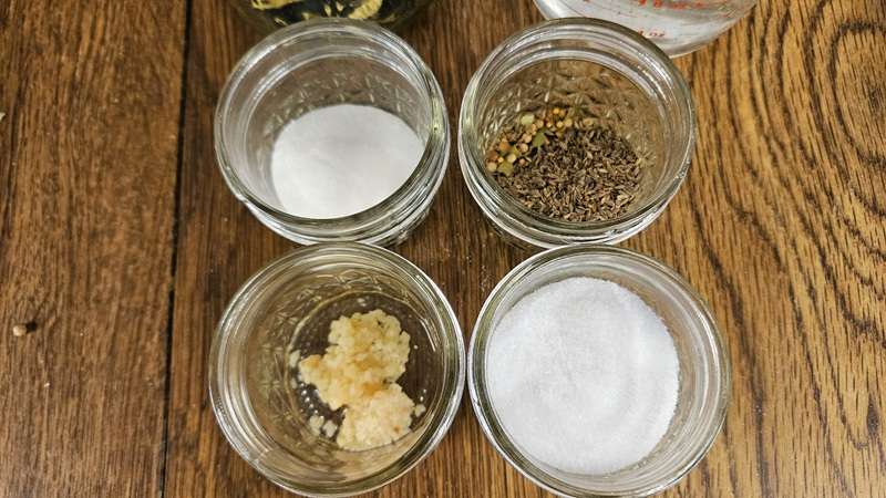 The spices for refrigerator pickles from dehydrated cucumbers are sugar, pickling spice, and dill seed (on the top), and garlic and sugar on the bottom.