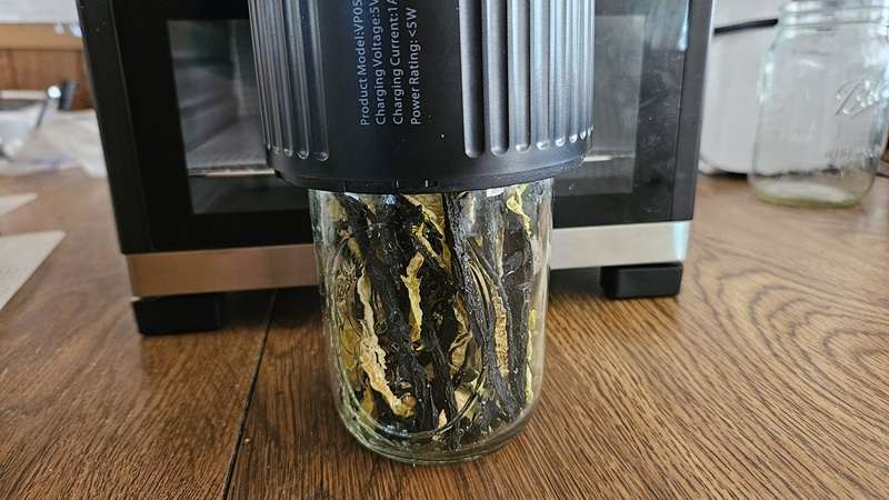 dehydrated cucumber spears in a mason jar, with a mason jar vacuum sealer on top.