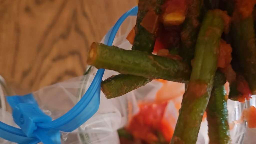 pouring green beans and tomatoes into empty freezer bags.