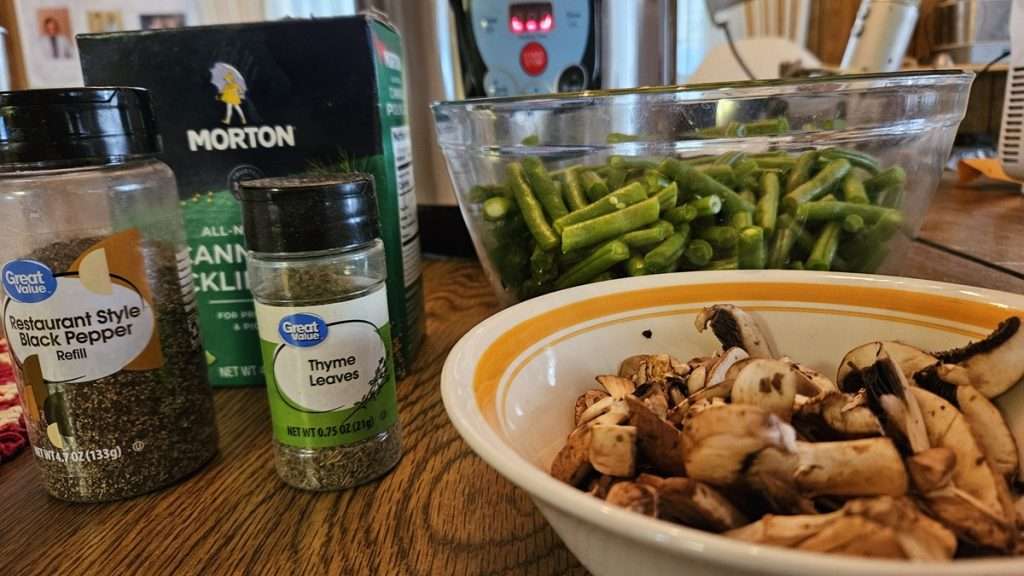 ingredients for home canned green beans and mushrooms, including canning and pickling salt, black pepper, thyme leaves, green beans, and mushrooms.
