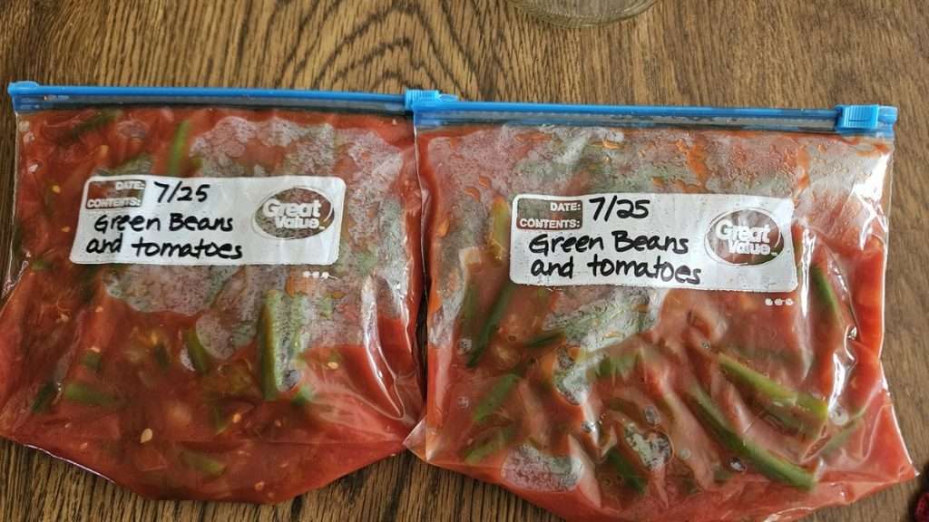 tomatoes and green beans in freezer bags laying flat.
