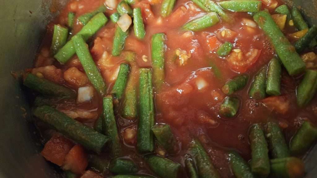 green beans, tomatoes, and onions mixed together in tomato sauce.