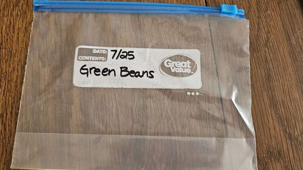 A freezer bag on a table. The bag has the date and the contents - green beans.