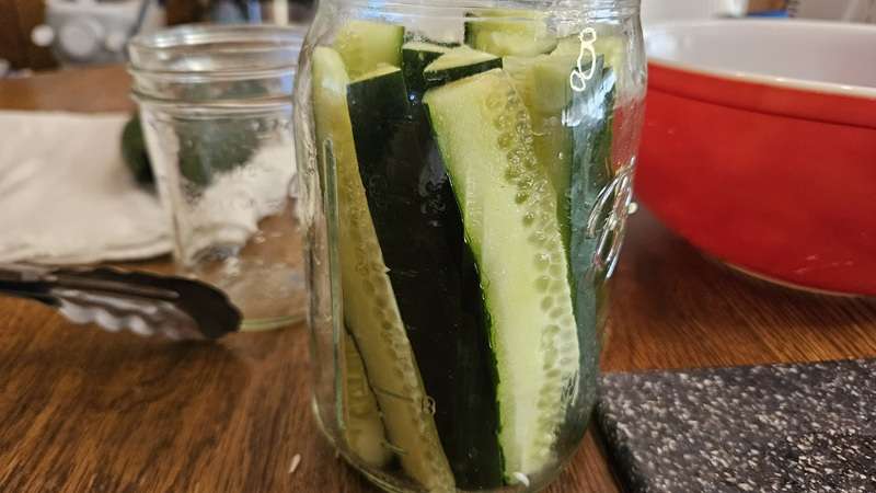 fresh cucumber spears in a mason jar from the side view.