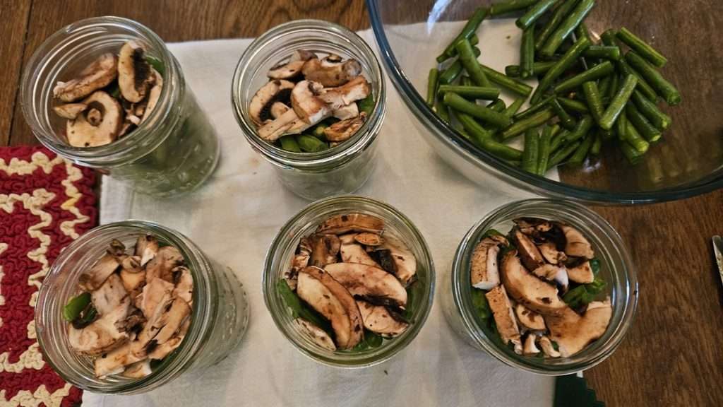 canning jars filled with green beans and mushrooms.