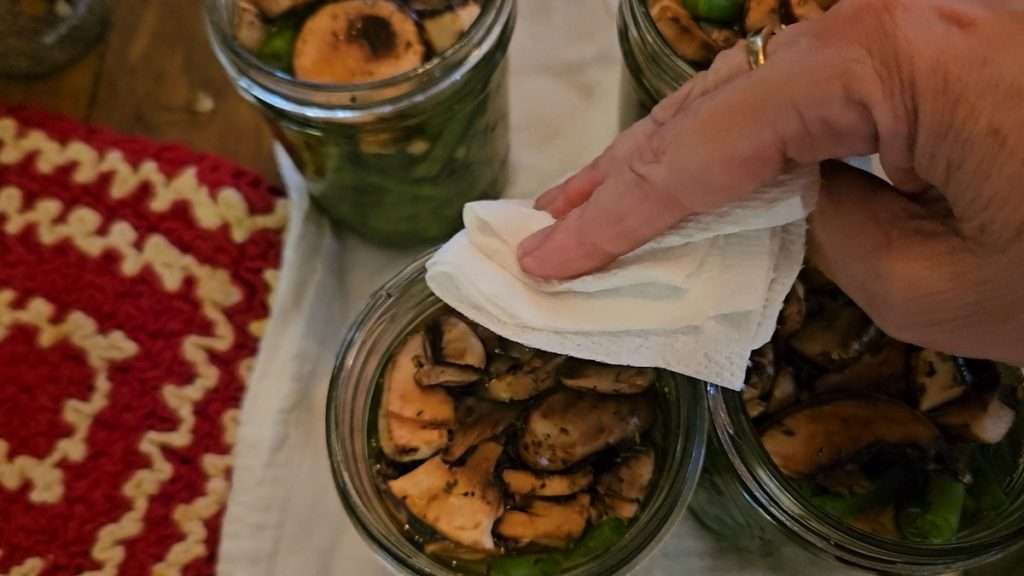 Wiping the rim of a filled canning jar