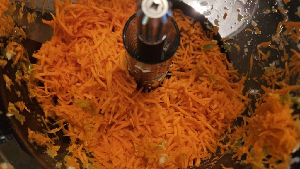 shredded carrots in a food processor bowl. Shredded carrots add a nice crunch to freezer slaw.