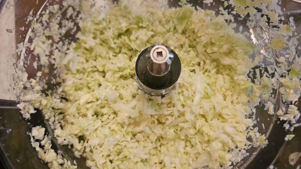shredded cabbage in a food processor container, for freezer slaw.