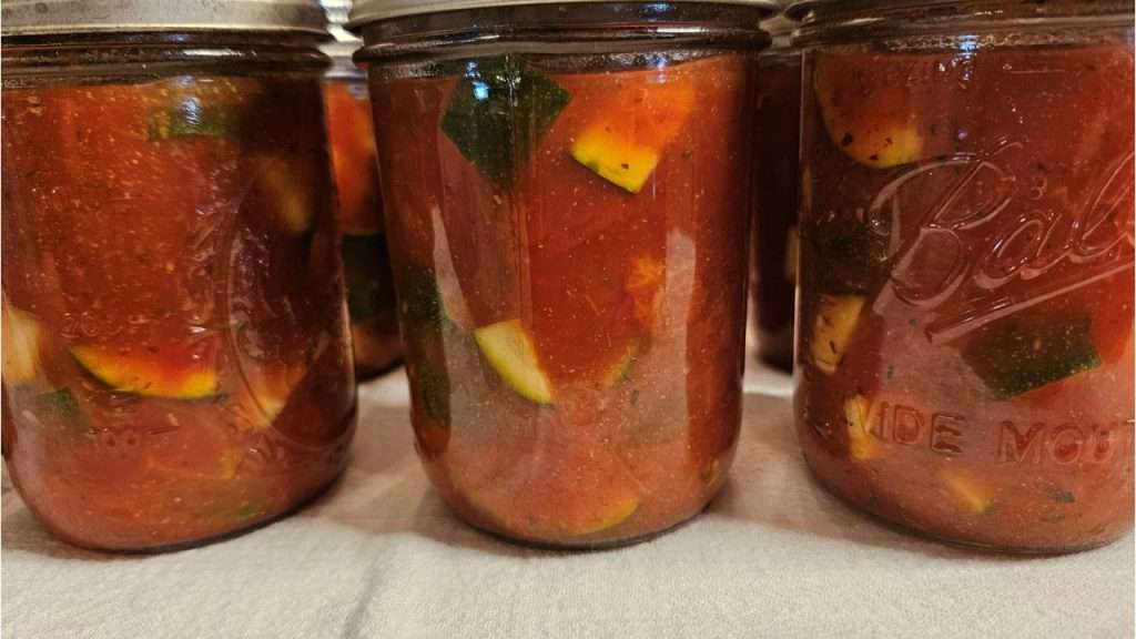 canning jars filled with zucchini and tomatoes waiting to go into the canner.
