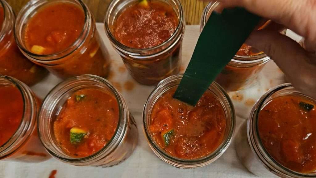 debubbling canning jars filled with zucchini and tomatoes